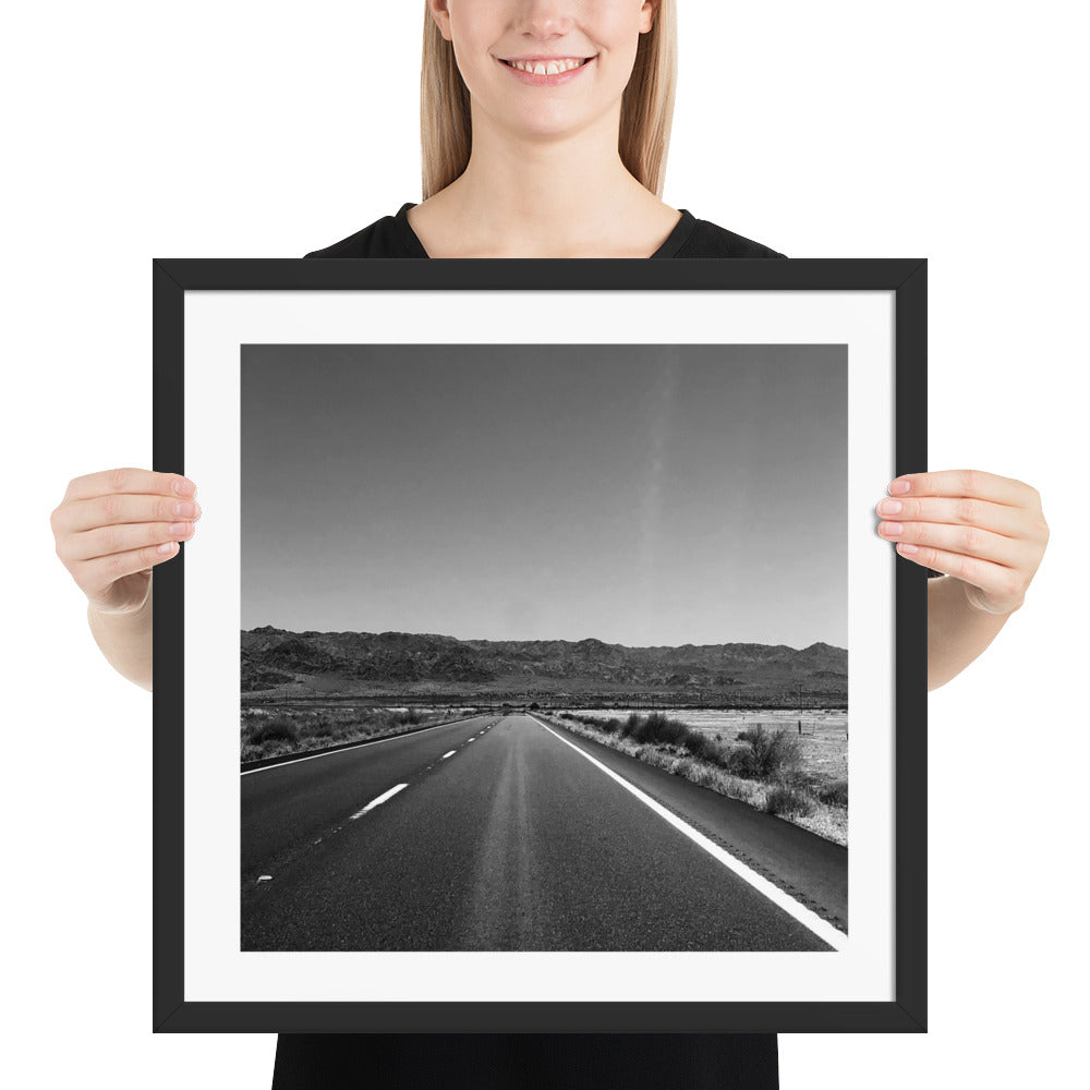 Person holding a framed black and white photograph of a road.