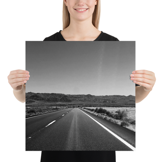 Photo paper poster of a black-and-white highway road held at the sides by hands